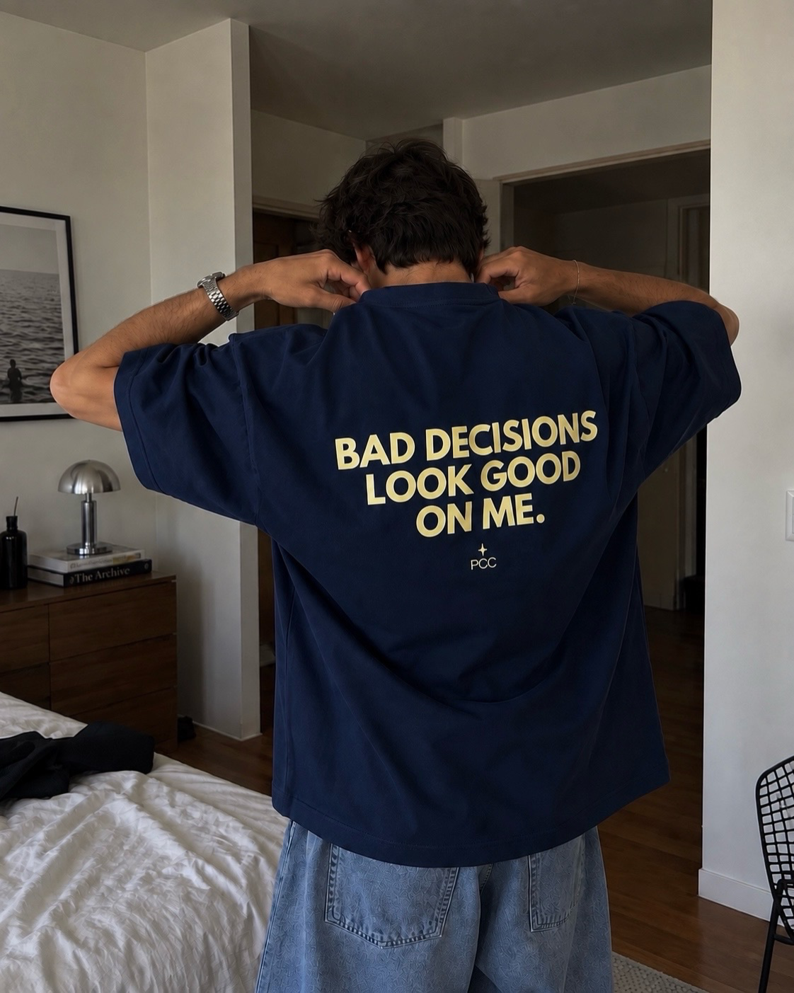 Hombre usando polo azul acero oversize de Peruvian Cool Club con estampado amarillo mantequilla en la espalda: “Bad Decisions Look Good on Me”.