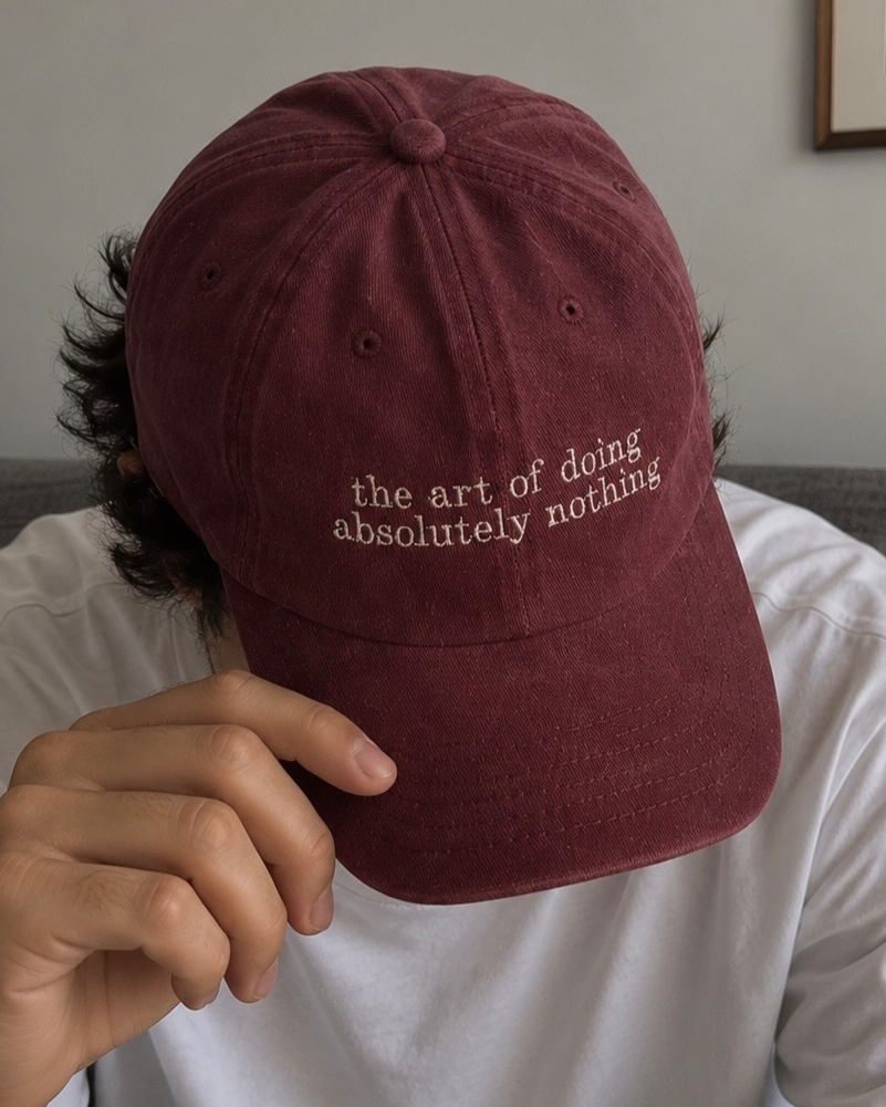 Gorra color vino de Peruvian Cool Club con acabado deslavado y frase bordada en beige: “The Art of Doing Absolutely Nothing”.