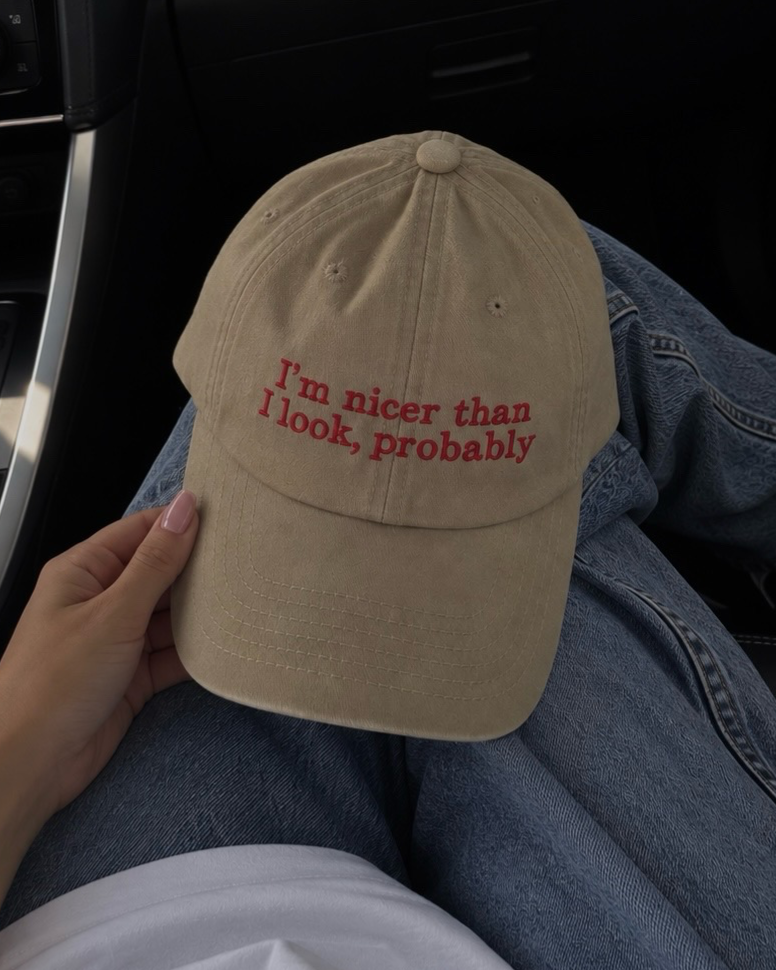 Gorra beige de Peruvian Cool Club con acabado deslavado y frase bordada en rojo vino: “I’m Nicer Than I Look, Probably”.
