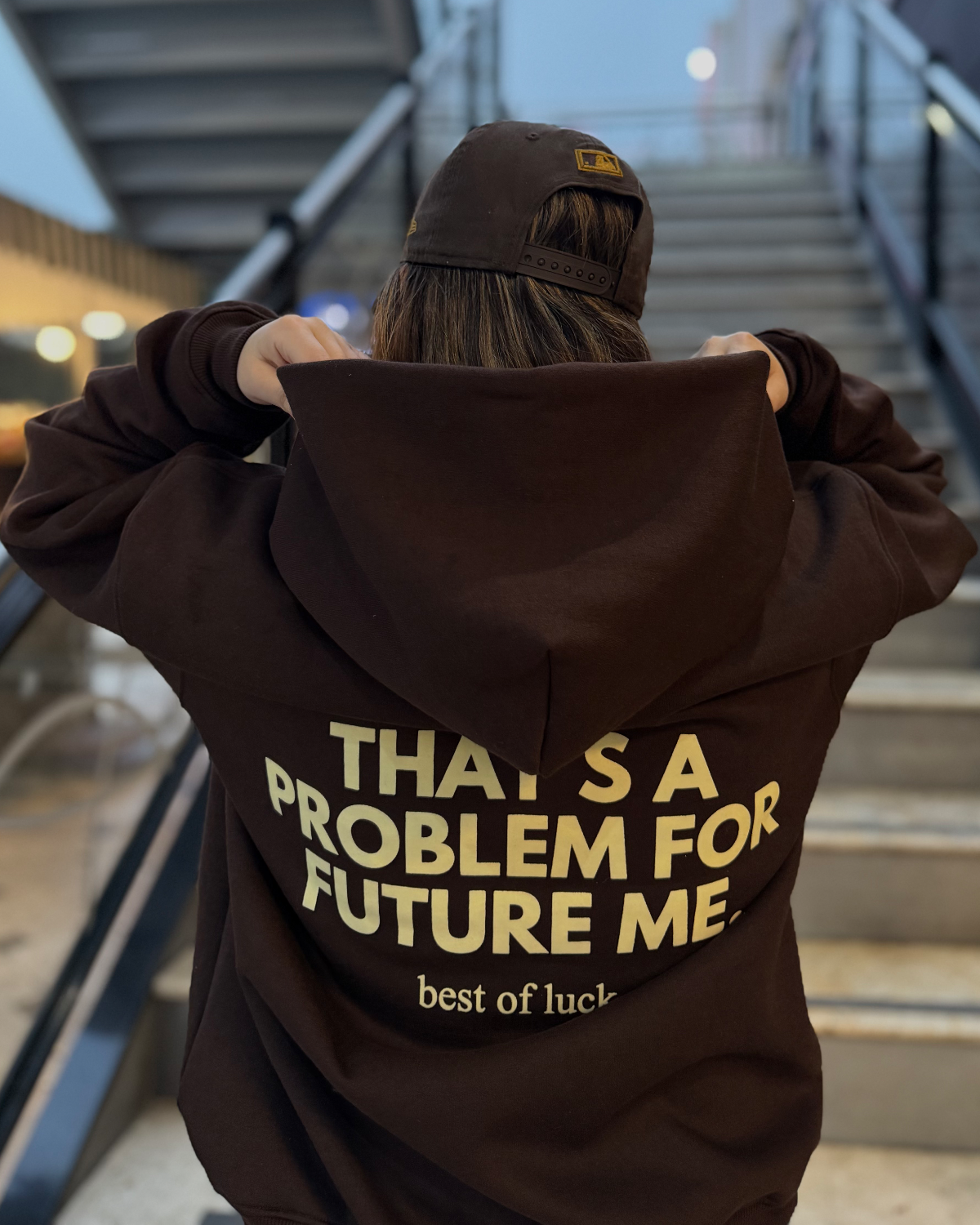 Hoodie marrón de Peruvian Cool Club con estampado amarillo mantequilla en la espalda: “That’s a Problem for Future Me. Best of Luck”.