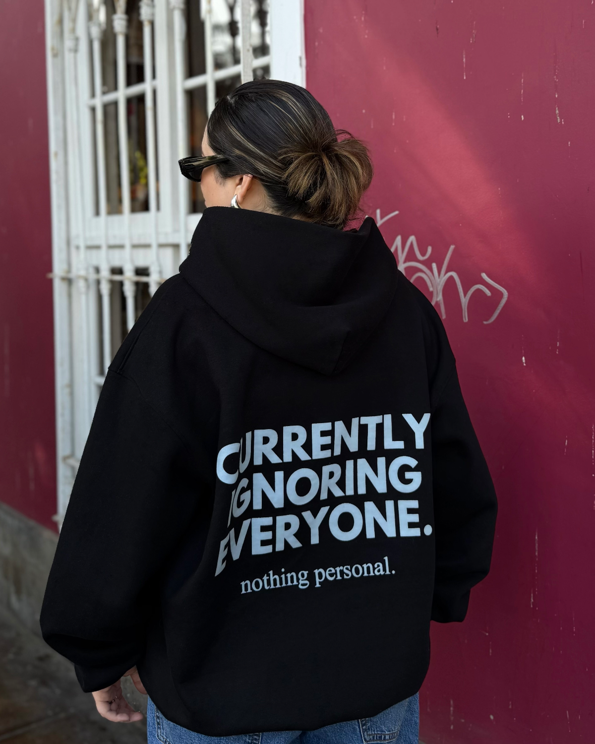 Hoodie negro de Peruvian Cool Club con capucha y estampado celeste hielo en la espalda: “Currently Ignoring Everyone. Nothing Personal.”