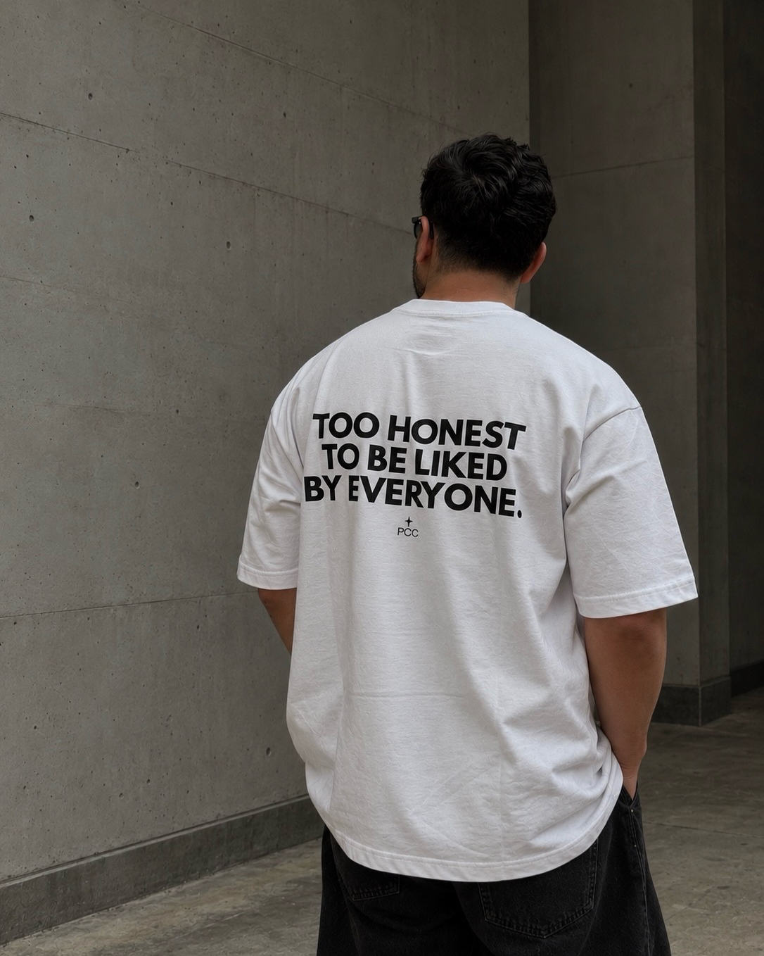 Hombre usando polo blanco oversize de Peruvian Cool Club con estampado negro en la espalda: “Too Honest to Be Liked by Everyone”.